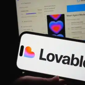 A smartphone showing the Lovable logo with its web platform for app building in the background.